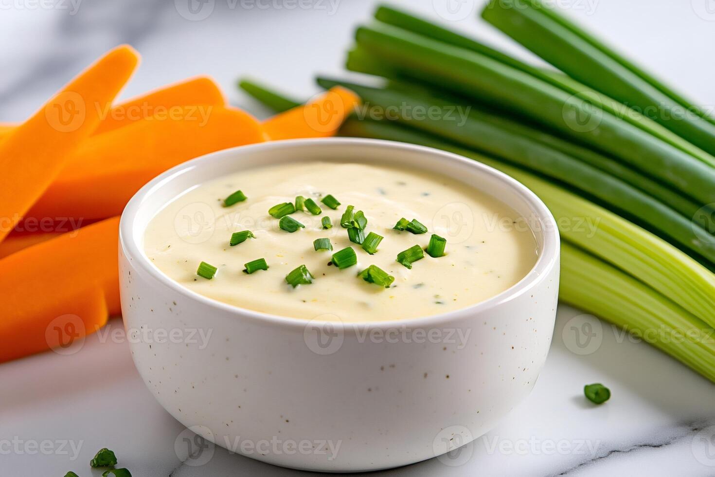 Creamy sauce with chives, carrots and spring onions sitting on a marble table photo