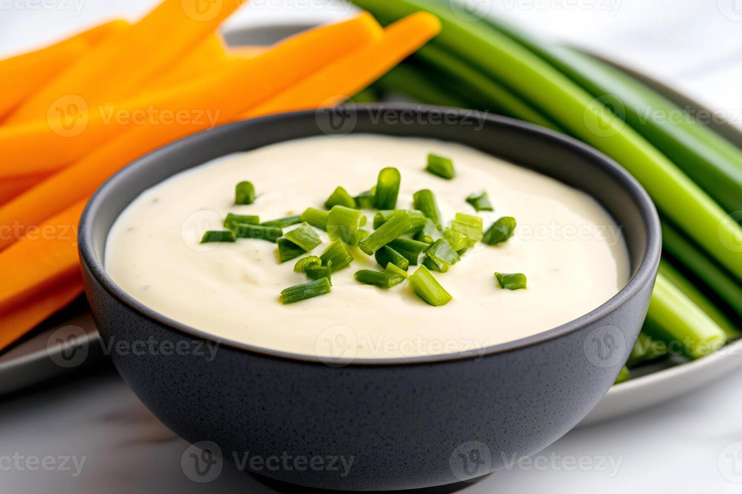 Bowl of vegetable dip with chopped chives, carrot and celery sticks photo