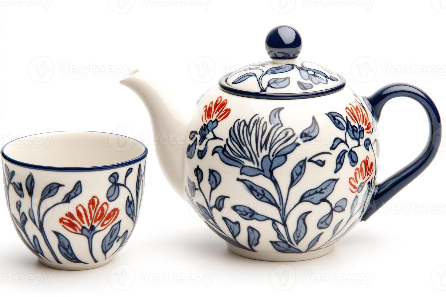 Ceramic teapot and teacup featuring blue and orange floral decoration standing on white background photo