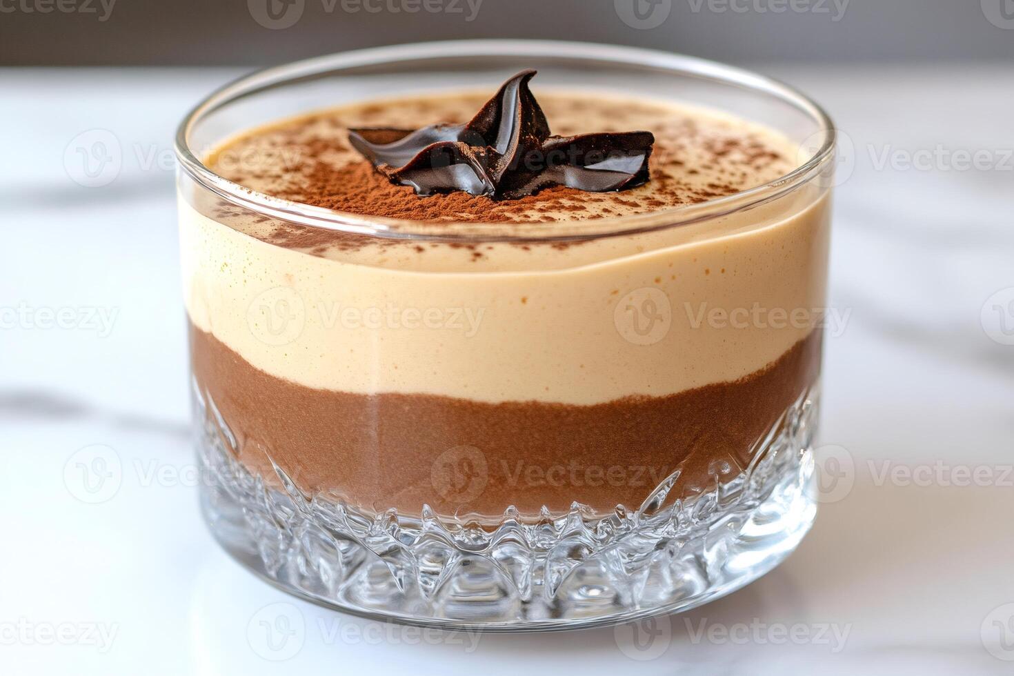 Delicious layered dessert with chocolate and cocoa powder topping in a crystal glass photo