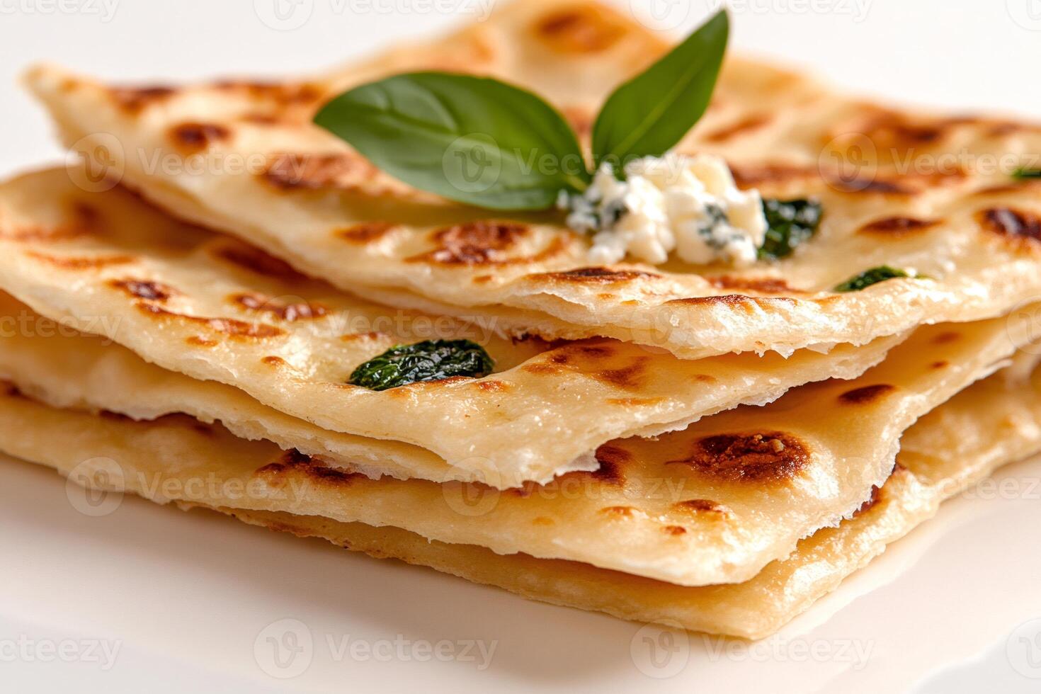 Stack of golden flatbreads garnished with fresh basil and cheese photo