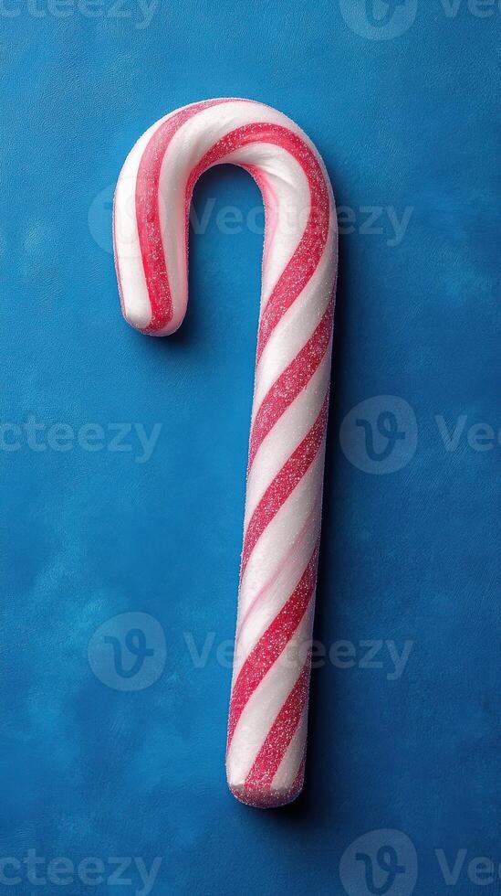 Brightly colored candy cane resting on a textured blue background brings festive vibes during the holiday season photo