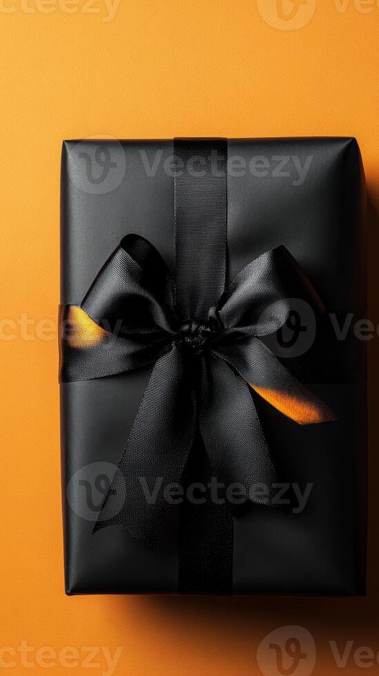 Elegant black gift box tied with a scarf on a bright orange background, perfect for any special occasion photo