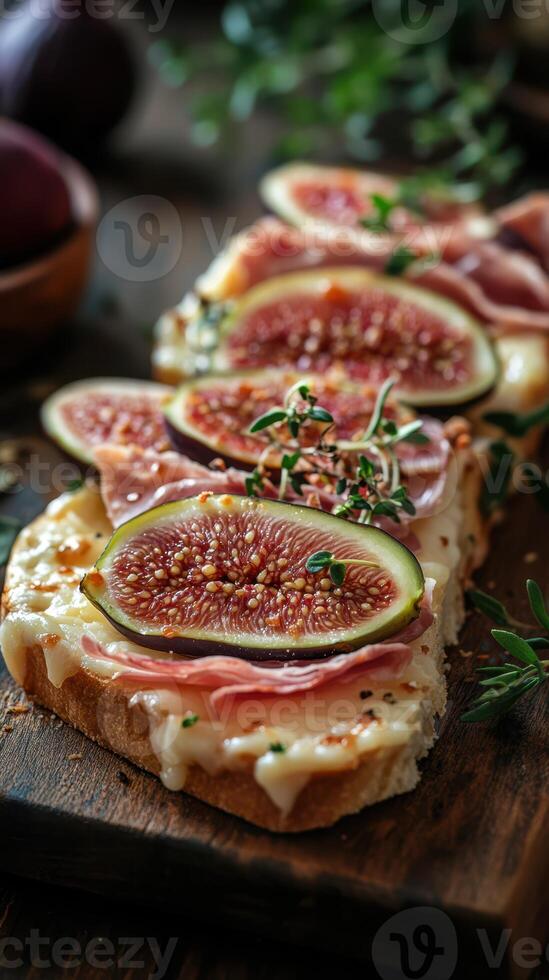 Delicious toasted bread topped with fresh figs, ham, and herbs served on a wooden board photo