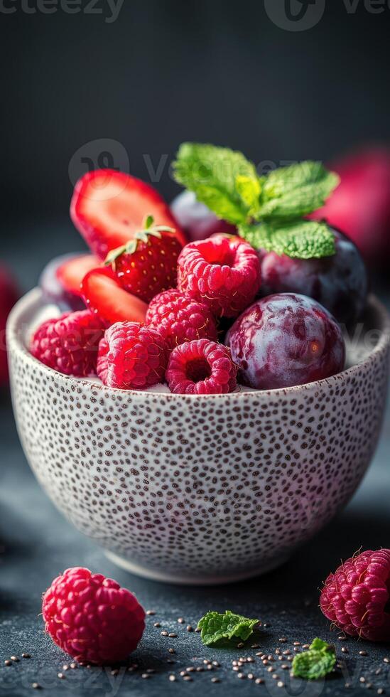 Fresh assortment of berries and fruits in a decorative bowl on a dark background showcasing vibrant colors and textures photo