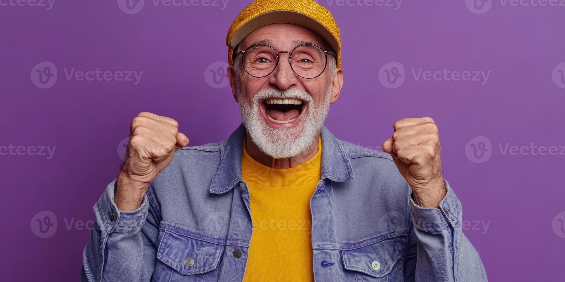 Elderly man expressing joy with raised fists against a purple background celebrating a moment of happiness photo