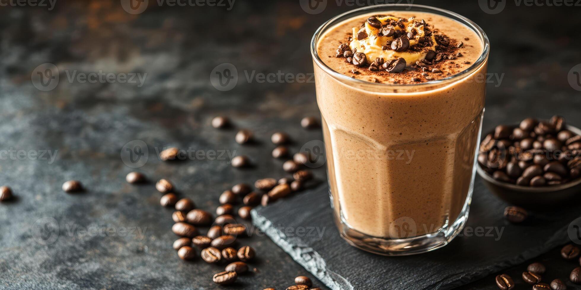Creamy coffee smoothie served in a glass with coffee beans scattered on a dark stone surface photo