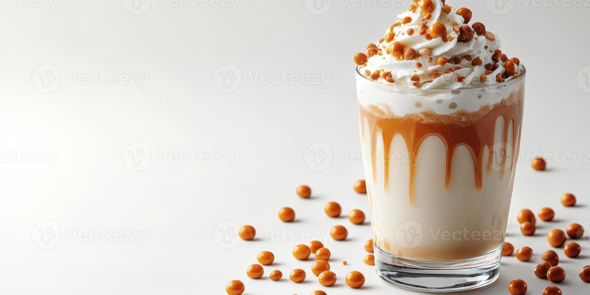Creamy dessert drink topped with whipped cream and caramel, adorned with crunchy toppings in a clear glass photo
