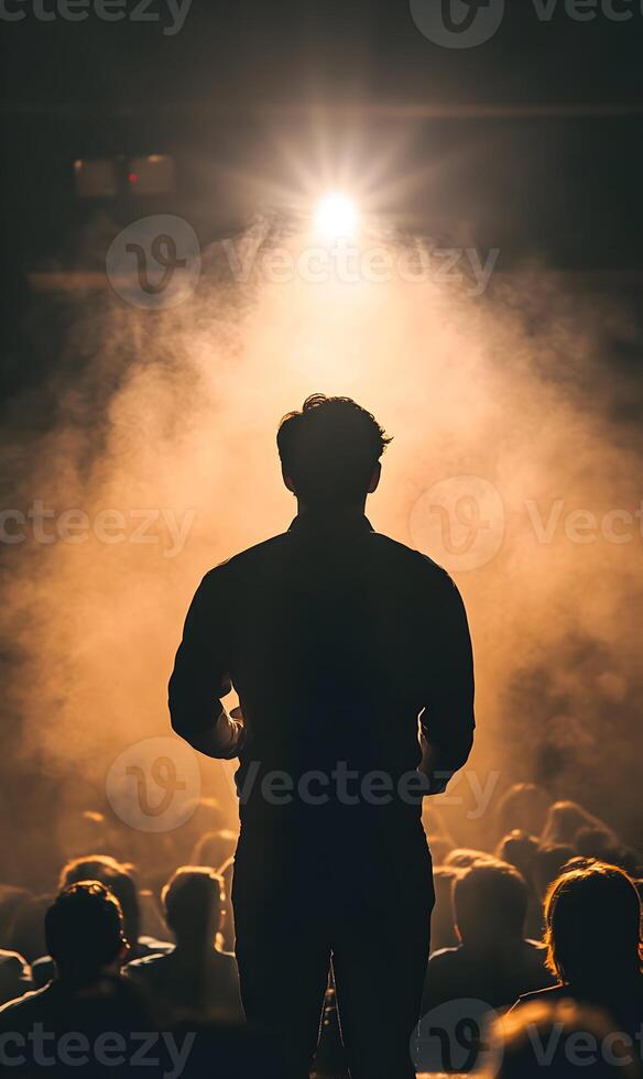 Silhouette of a speaker addressing an audience in a dimly lit, smoky environment at the event photo