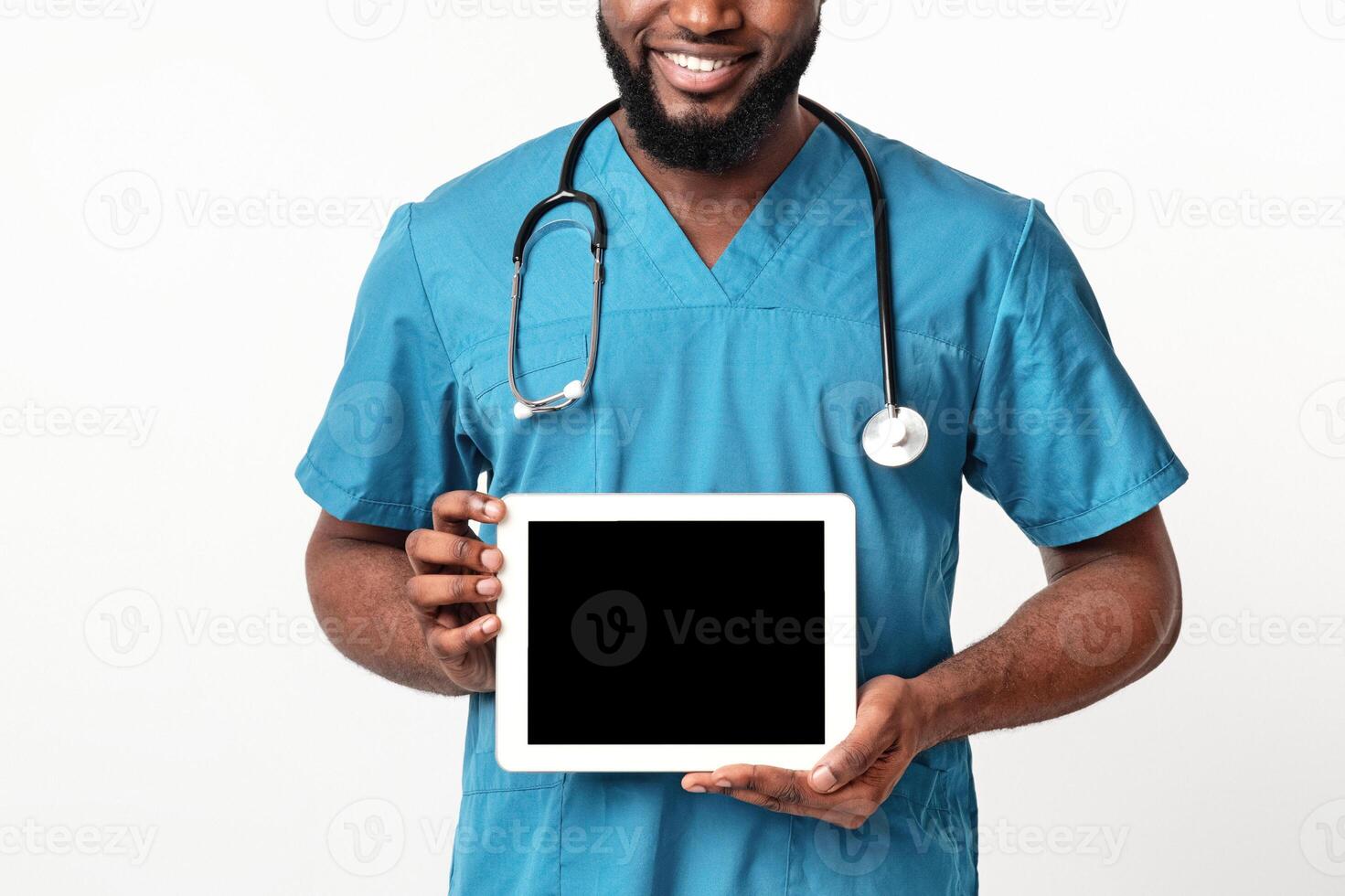 African American friendly doctor in blue uniform demonstrating empty digital tablet screen, white background photo