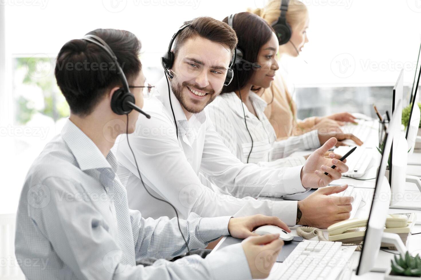 Happy male technical support operators having friendly chat at call centre. Positive millennial hotline consultants communicating at workplace. Helpline service concept photo