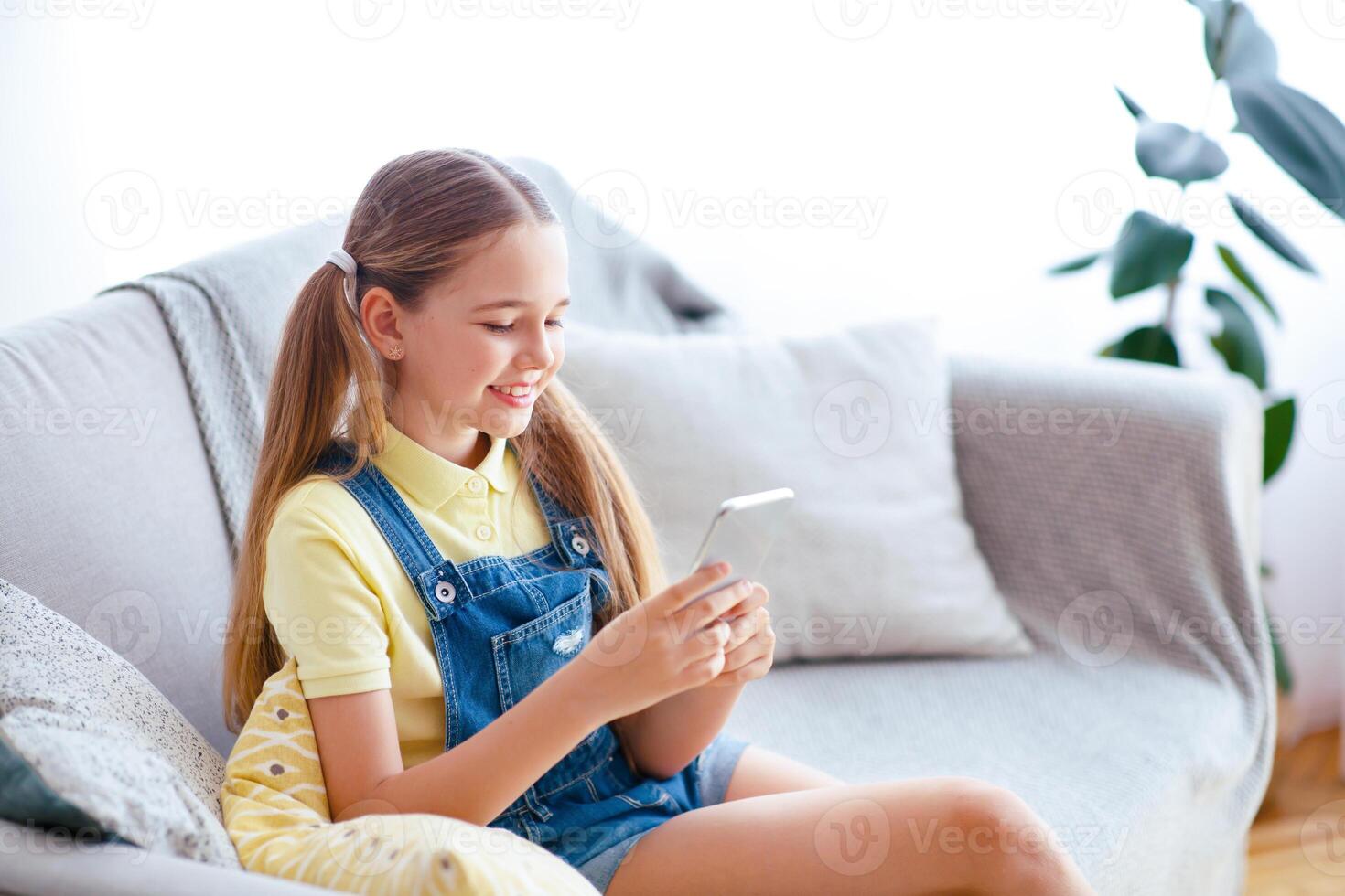 Amazing Application. Casual glad teenage kid with ponytails using smart phone, typing and sending message photo