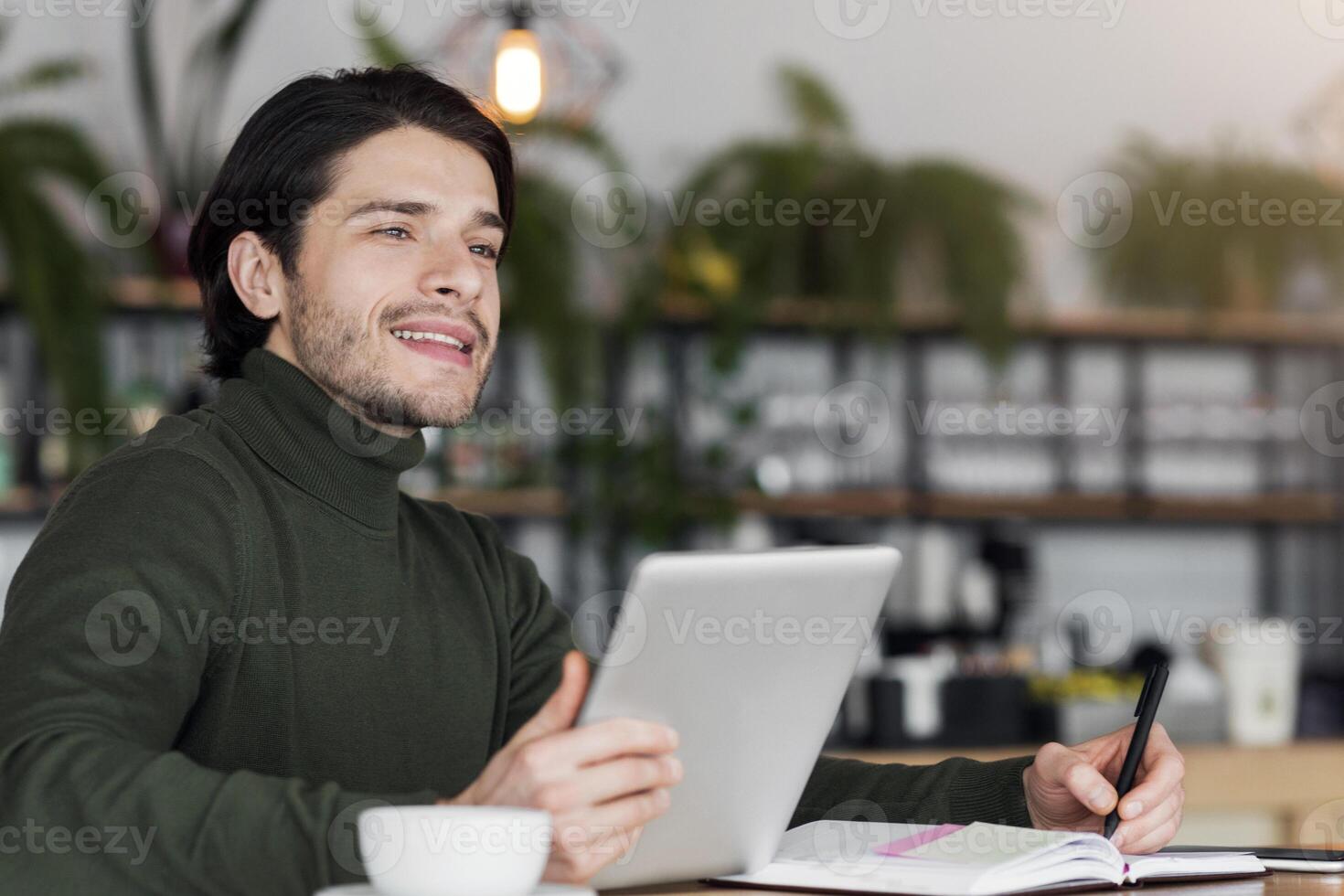 Dreamy male freelancer working on new project at cafe, using digital tablet, copy space photo