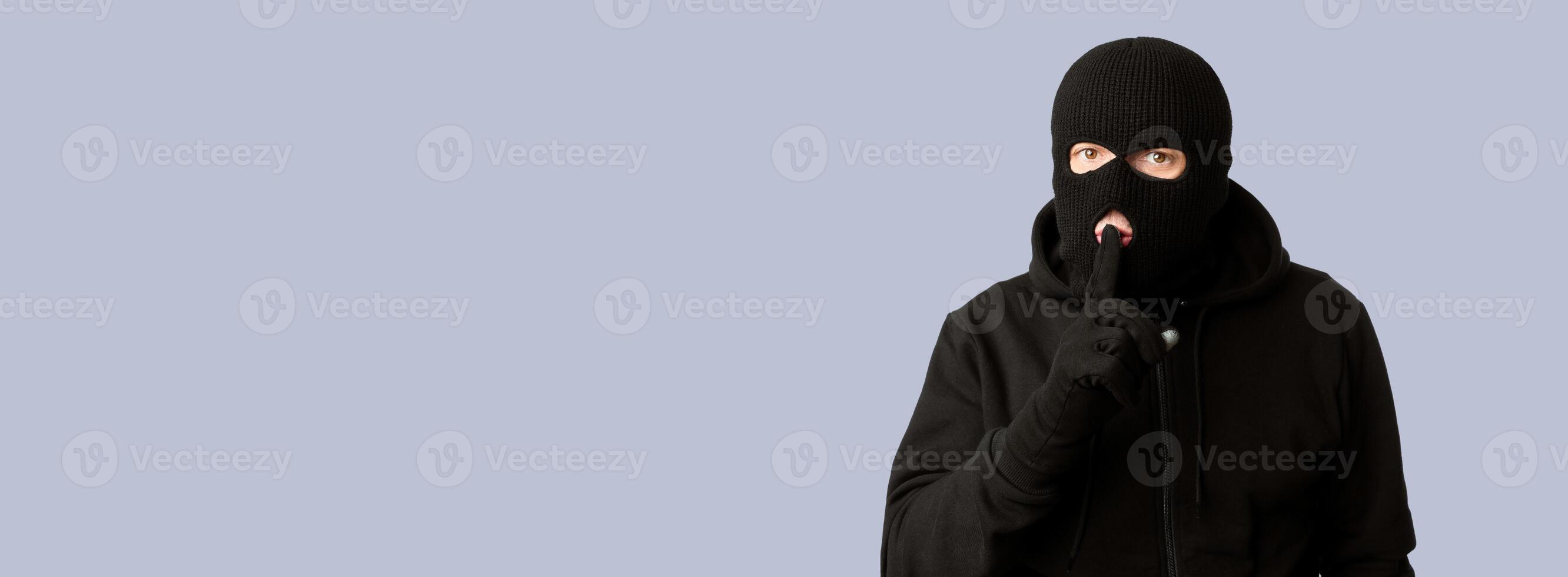 Don't Tell Anybody. Headshot of sneaky looter showing silence gesture, isolated over white studio background photo