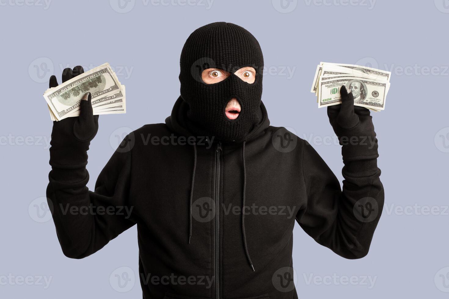 Being Caught Concept. Arrested masked thief holding money, raising arms isolated on white studio background photo