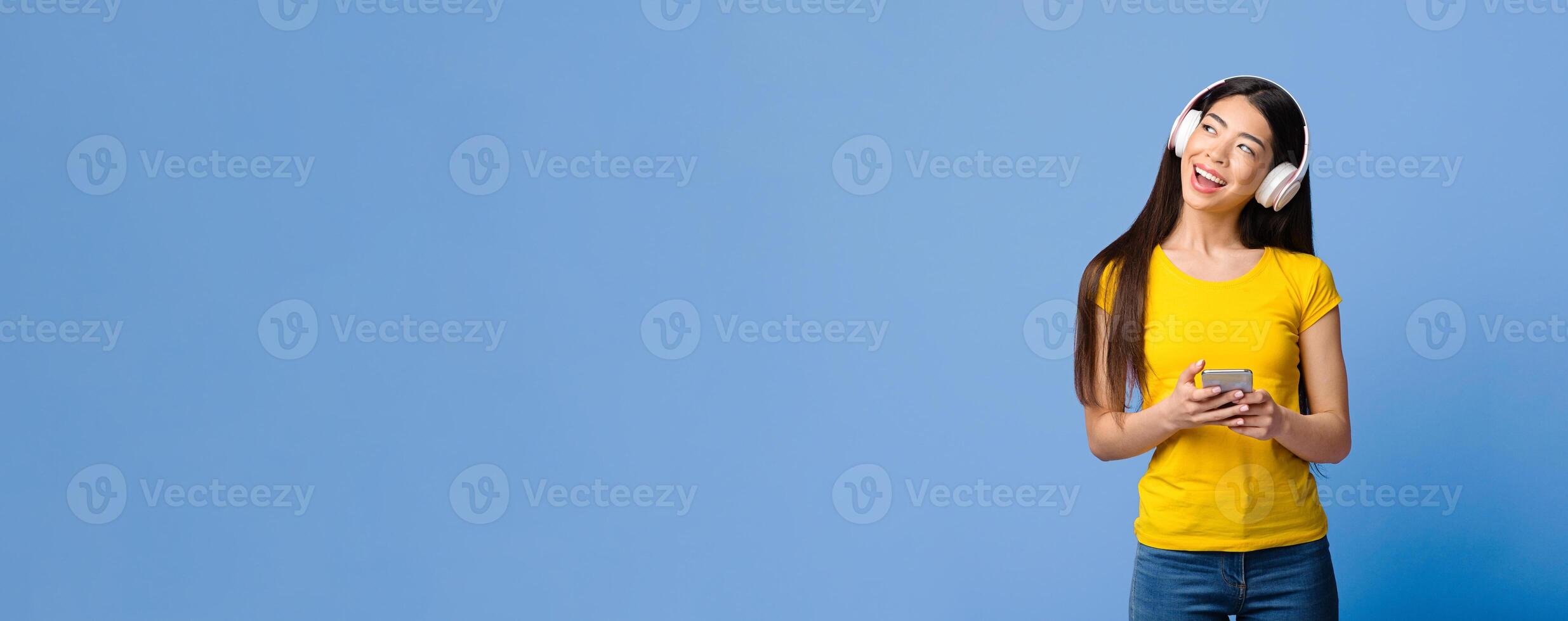 Joyful Asian Girl Listening Music On Smartphone With Wireless Headphones And Looking At Copy Space On Purple Background, Panorama photo