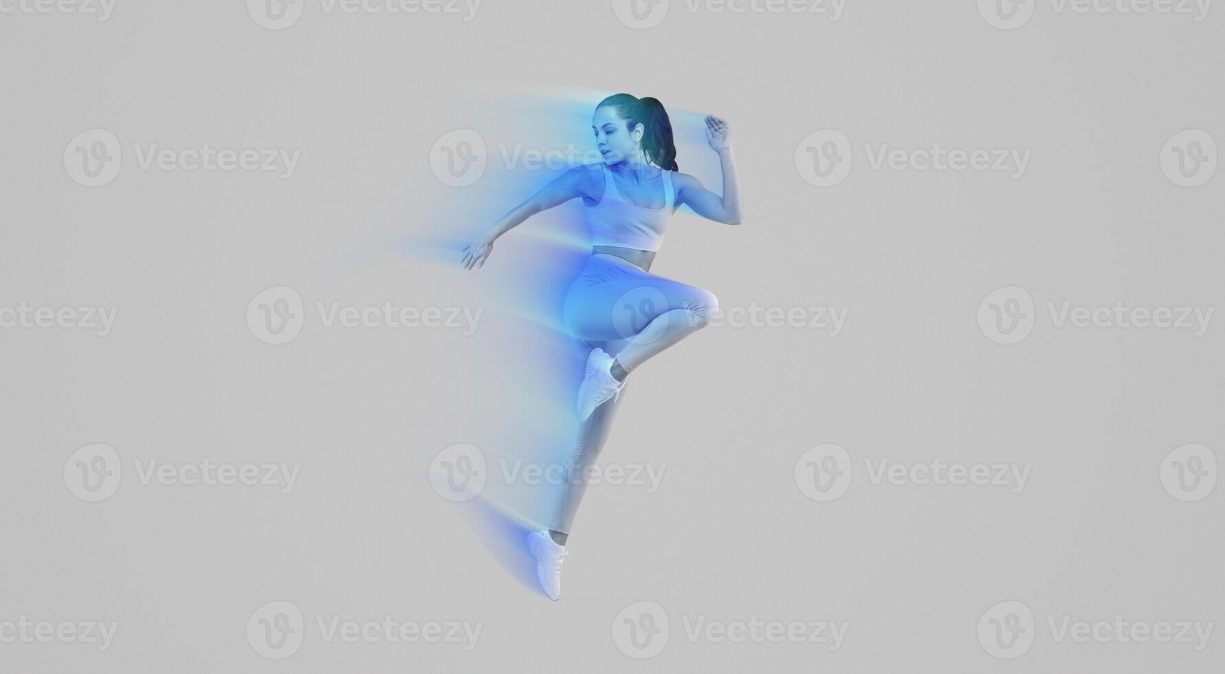 A woman wearing a blue outfit is captured mid-air as she jumps. Her joyful expression is evident as she defies gravity. The background is grey, emphasizing her movement, copy space photo