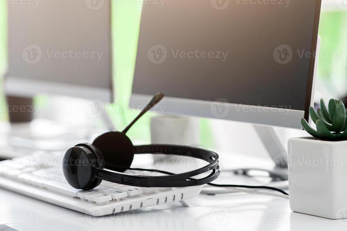 Call center and customer service concept. Computer monitor with blank space for your design and VOIP headset on desk in office photo