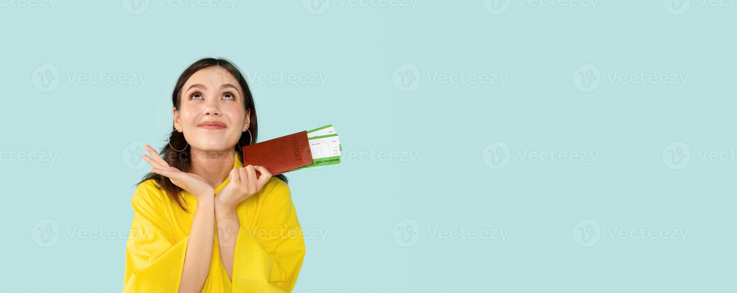 Cheerful Young Lady Holding Passport With Tickets And Looking Up, Ready For Vacation Trip, Woman Recommending Good Travel Agency, Standing Over Blue Studio Background, Copy Space photo
