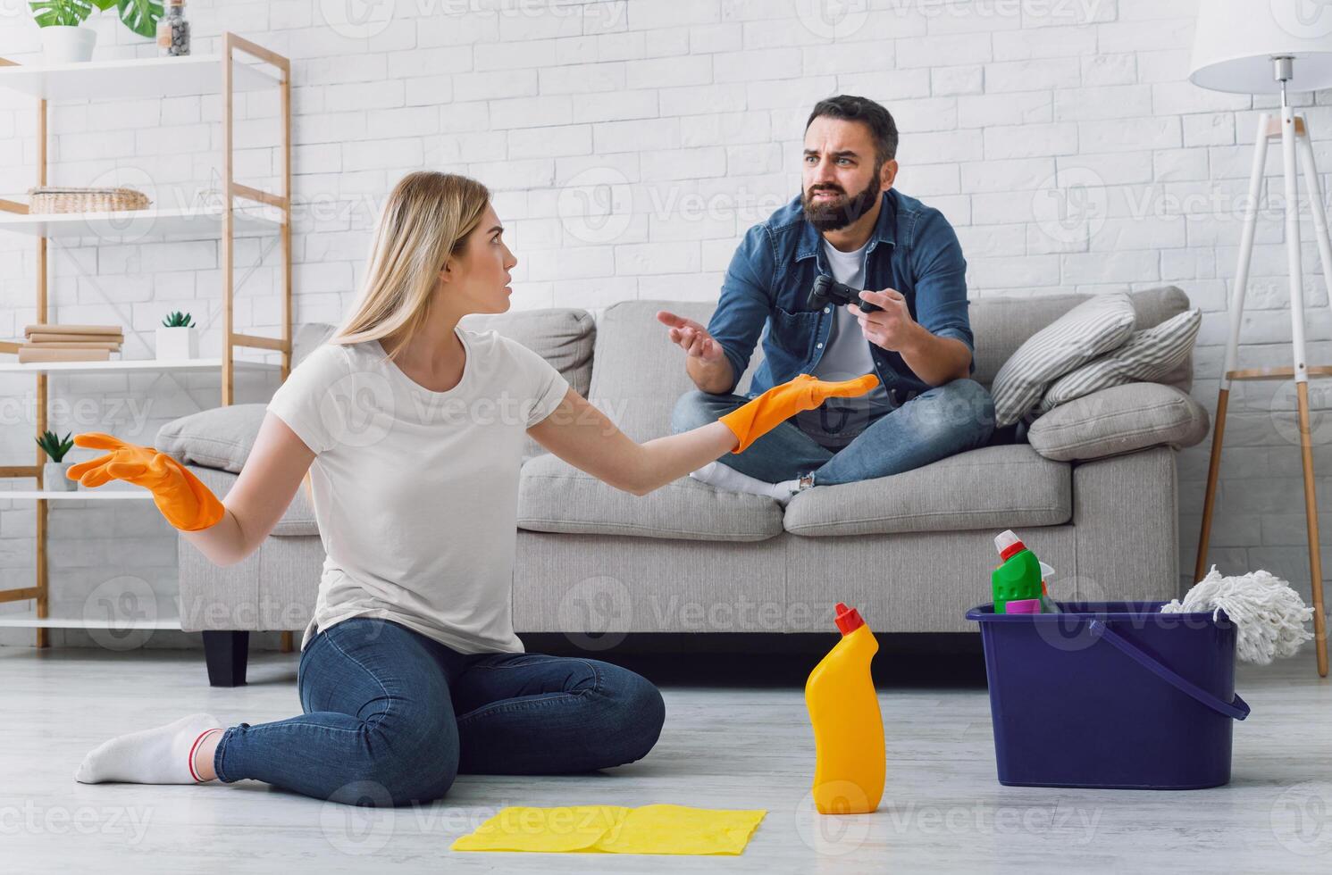 Quarrel over indifference in family. Wife sitting on floor swears with husband, playing computer games, free space photo