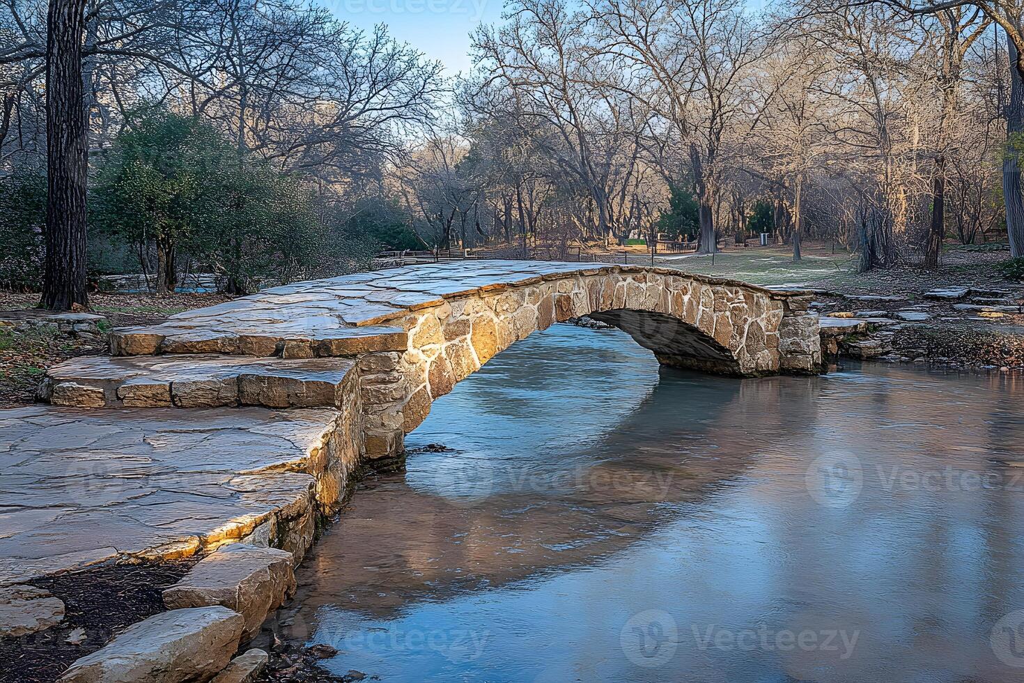 Rustic Stone Bridge Over Tranquil Stream in Serene Winter Landscape photo