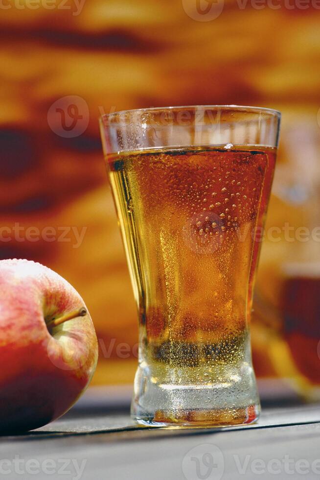 A glass of liquid and an apple on a table photo