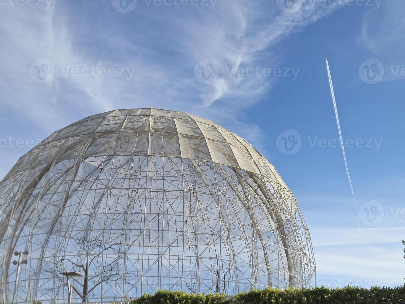 A large white dome with a contrail in the sky photo