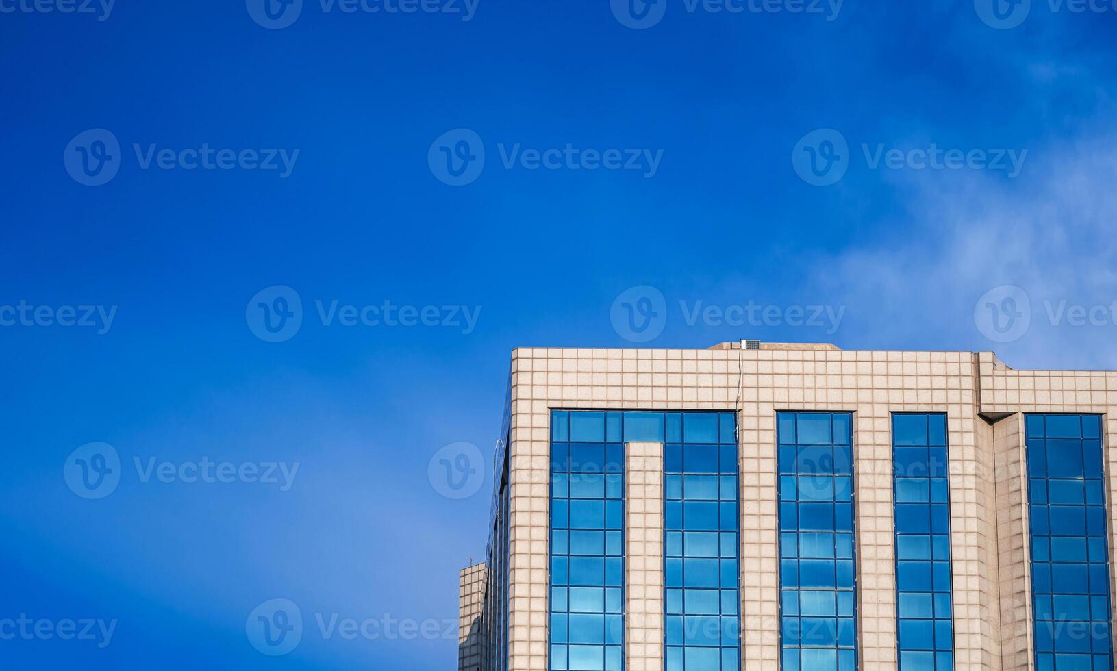 A modern office building stands prominently against a vibrant, clear blue sky photo