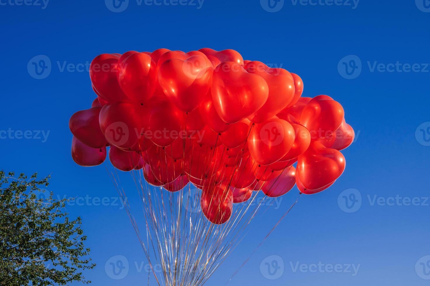 bunch of red balloons in shape of a heart on background of blue sky photo