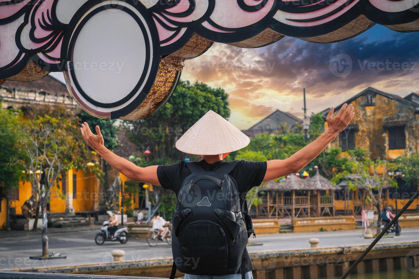 back of male tourist in a Vietnamese hat on old bridge in ancient town in Hoi An in Vietnam in Asia photo