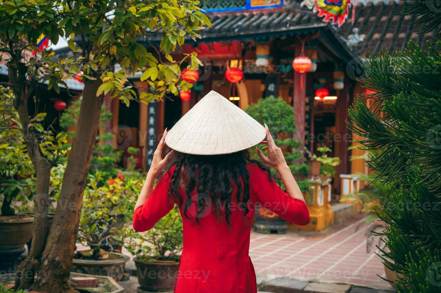 Back of a female tourist traveler in a Vietnamese cone hat Non La at Buddhist temple in Hoi An in Vietnam in Asia photo
