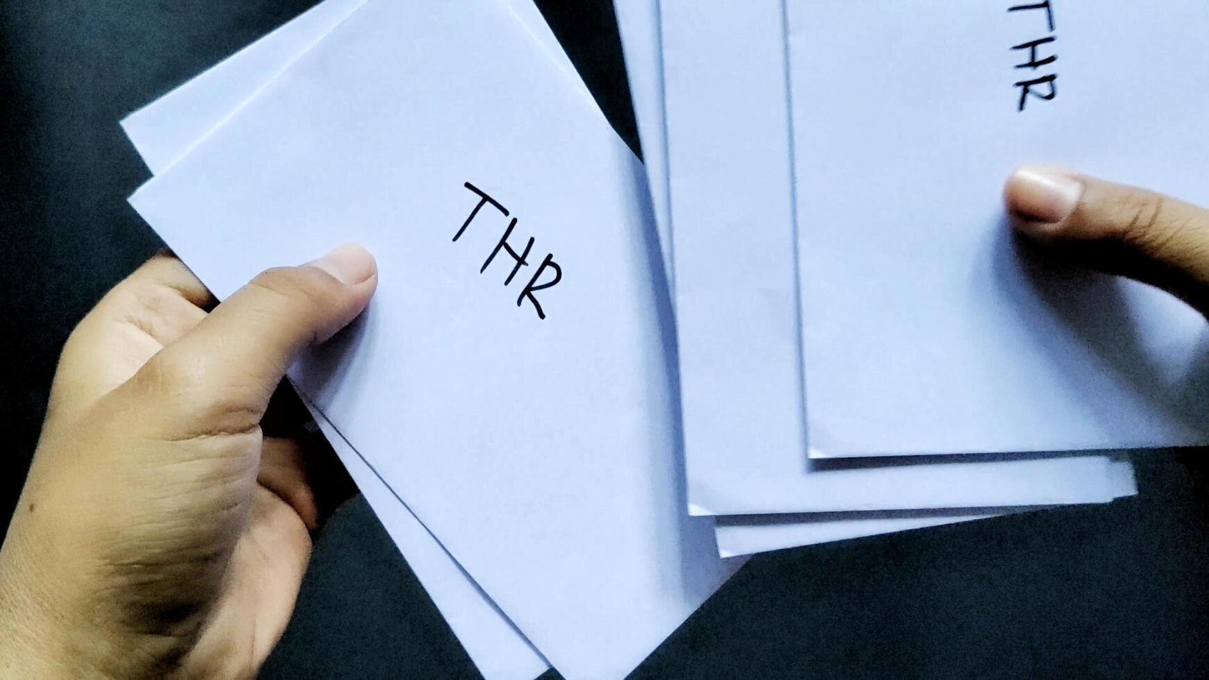 A man count several envelopes labeled THR. This envelope contains an allowance of 1 month's salary, which in Indonesia is usually given to employees before the Eid al-Fitr holiday photo