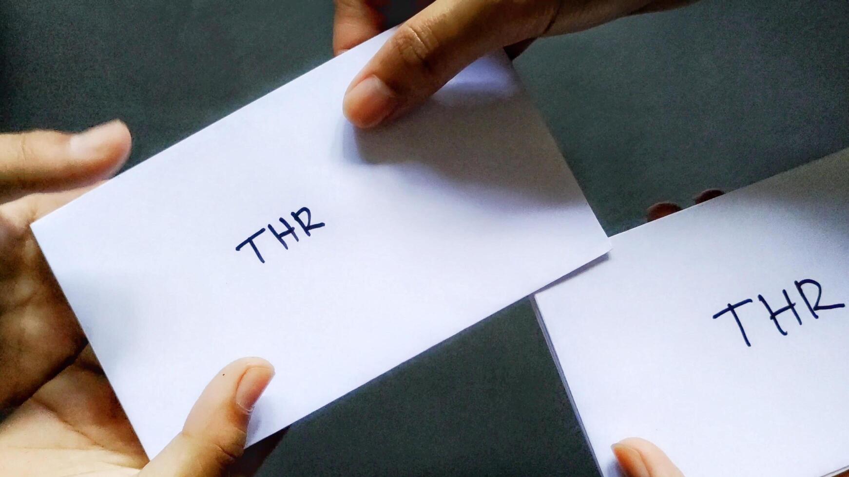 Photo concept of someone giving salary allowances in an envelope marked THR. This THR is a salary allowance that is usually given to employees before the Eid al-Fitr holiday in Indonesia