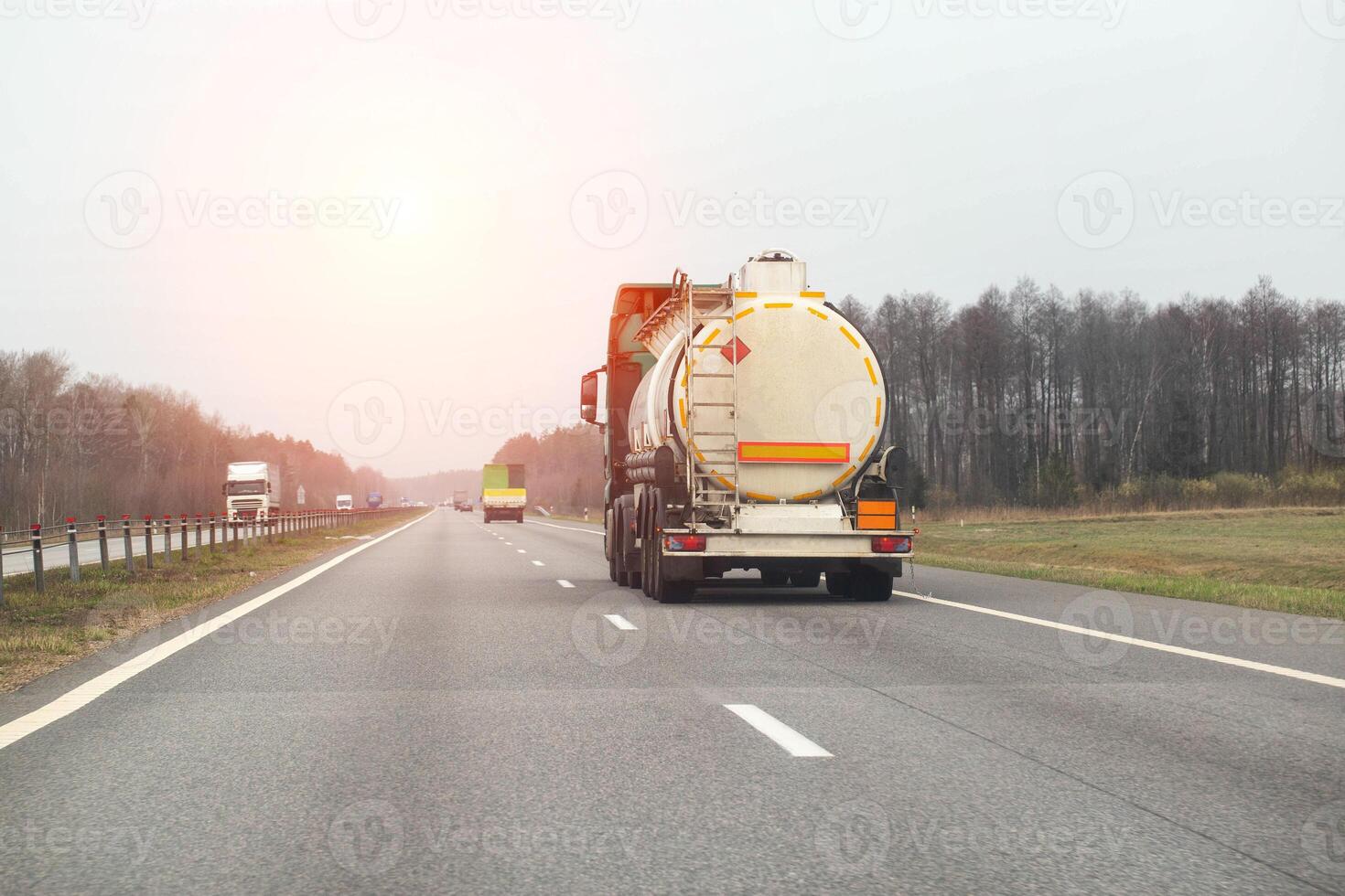 A tanker truck with a semi-trailer transports a dangerous cargo of toxic chemicals along a country road in the spring. Copy space for text photo