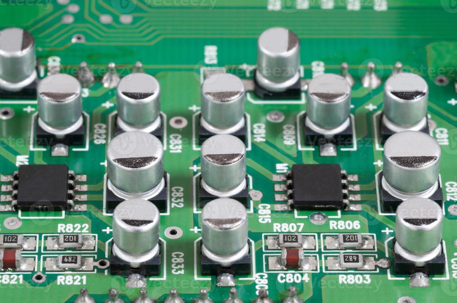 Close-up view of green electronic circuit board showing aluminum capacitors and integrated components with intricate connections photo