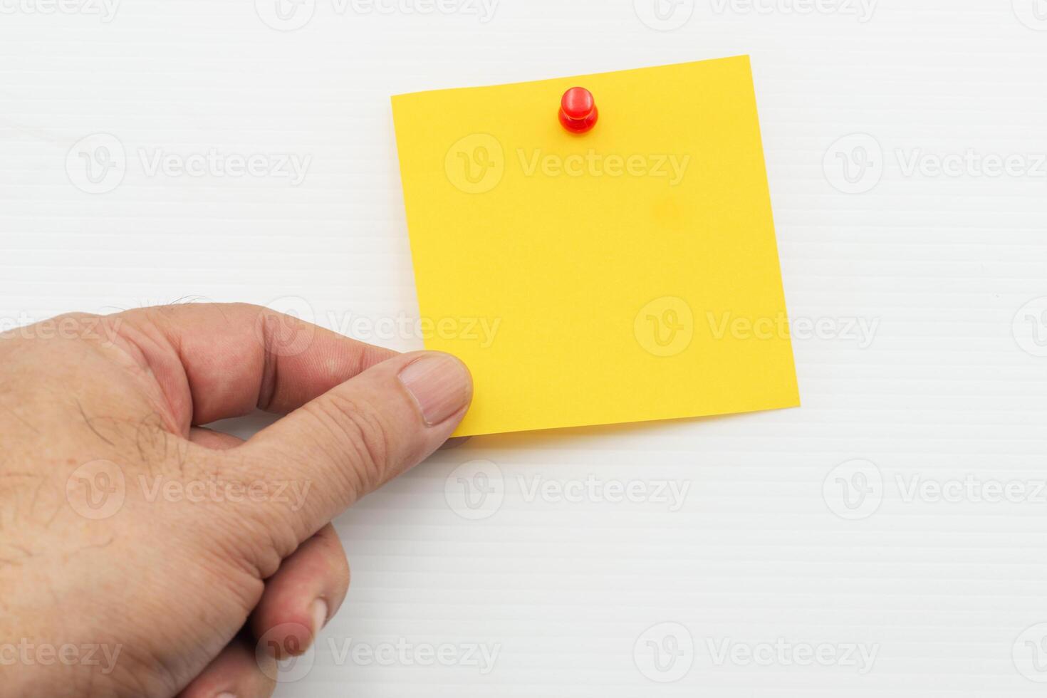 Hand holding yellow post note paper attached with red pin isolated on white background photo