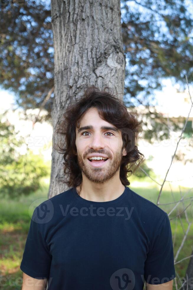 Young Long Hair Man Marveled In Nature Near A Tree photo