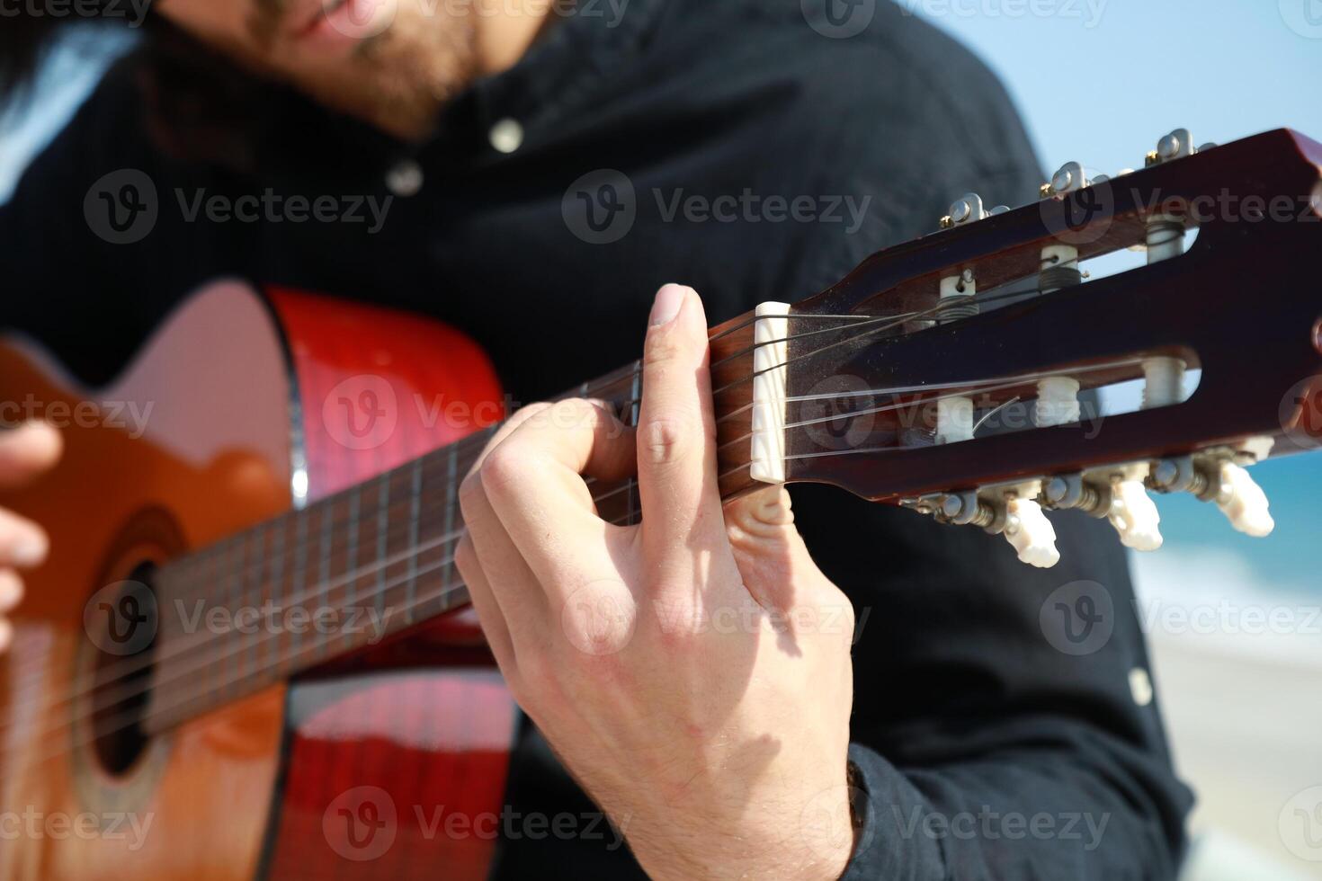 Man Plays Classical Guitar On The Beach Near The Sea In Summer photo