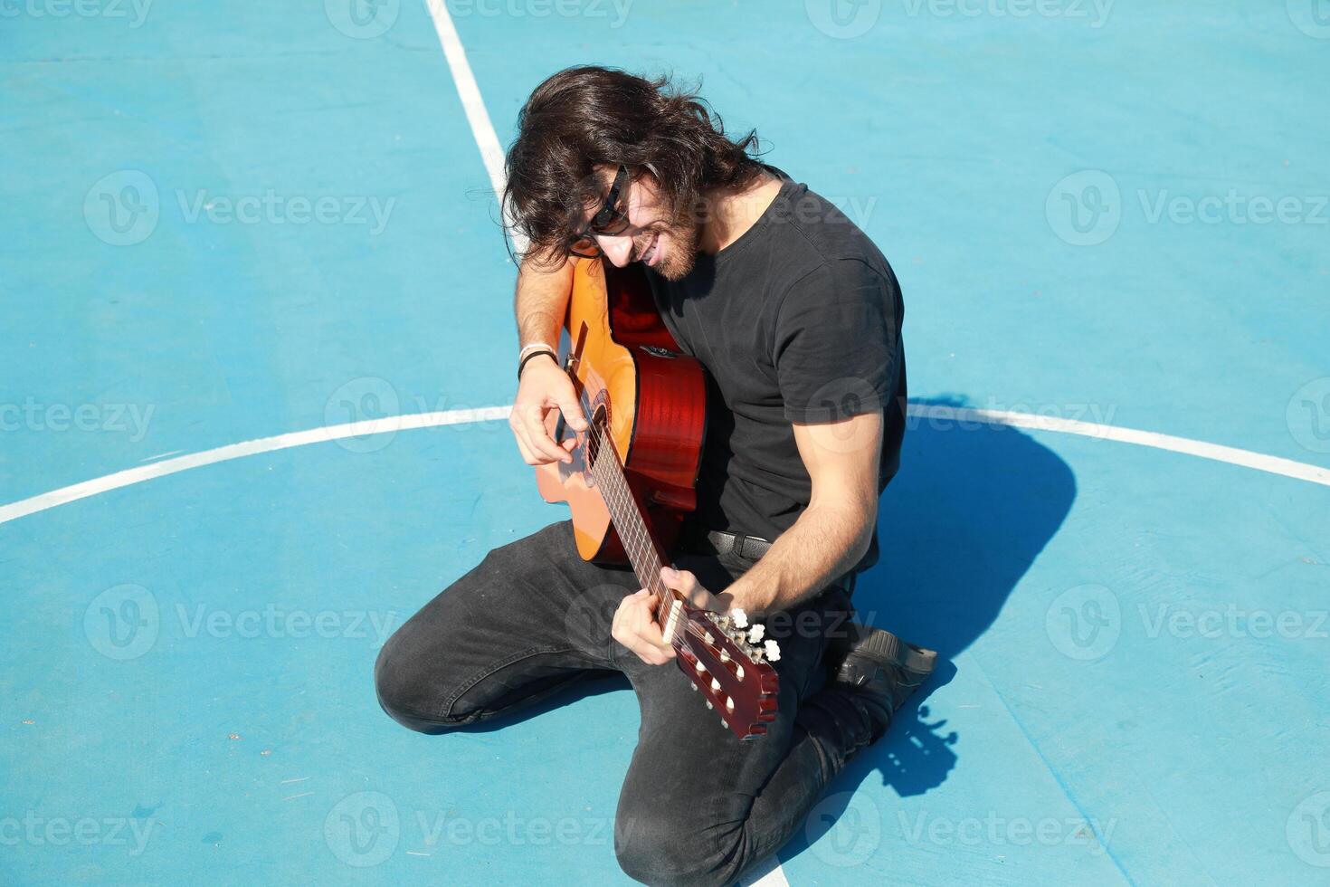 Long Hair Man Plays Classical Guitar Unleashed Outside In Blue Field photo