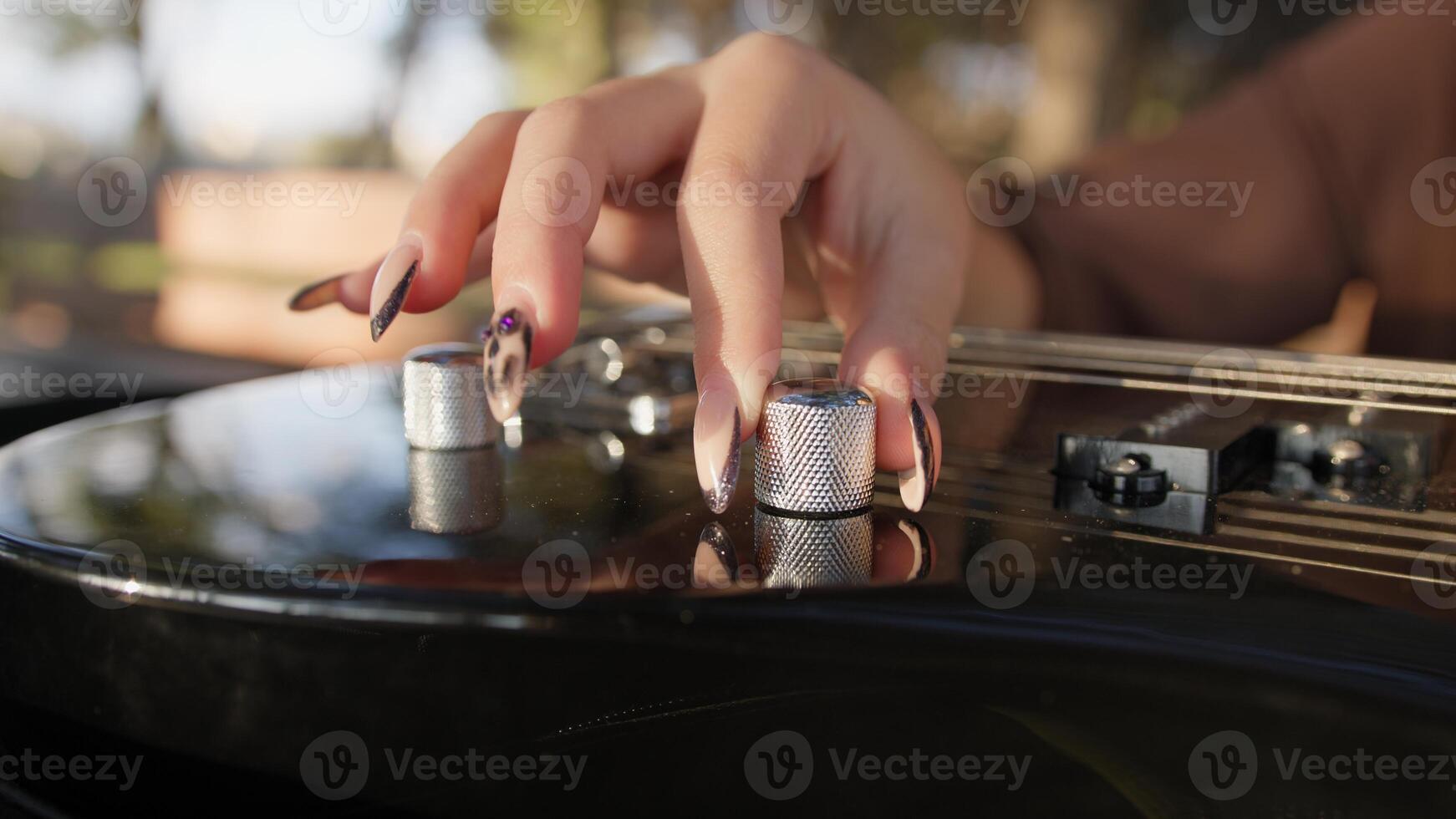 Woman Hands Turn Knobs For Tone Of Electric Bass Musical Instrument photo