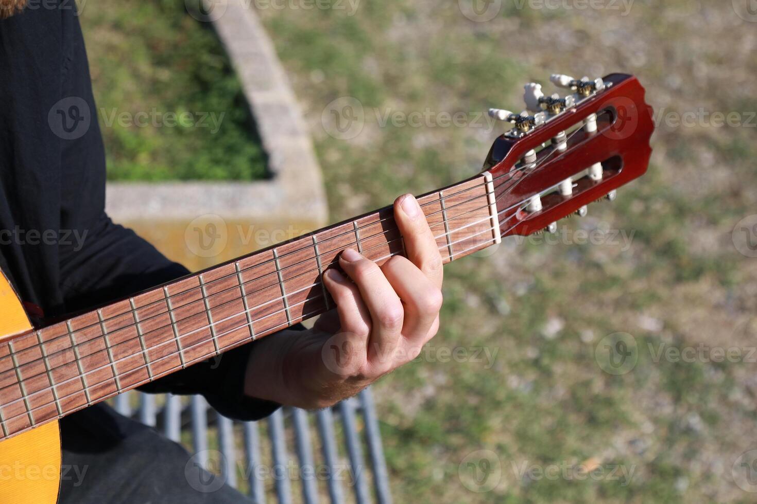 Male Street Artist Enjoys Playing Classical Guitar In A City Park photo