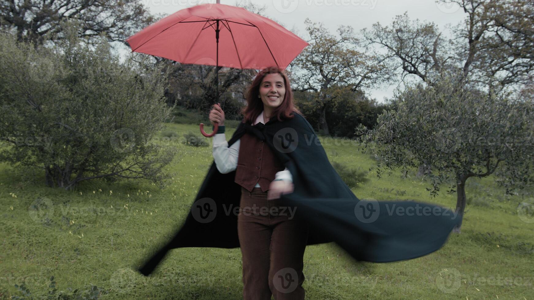 Happy Woman Spins On A Meadow During The Rain In Winter With Red Umbrella photo