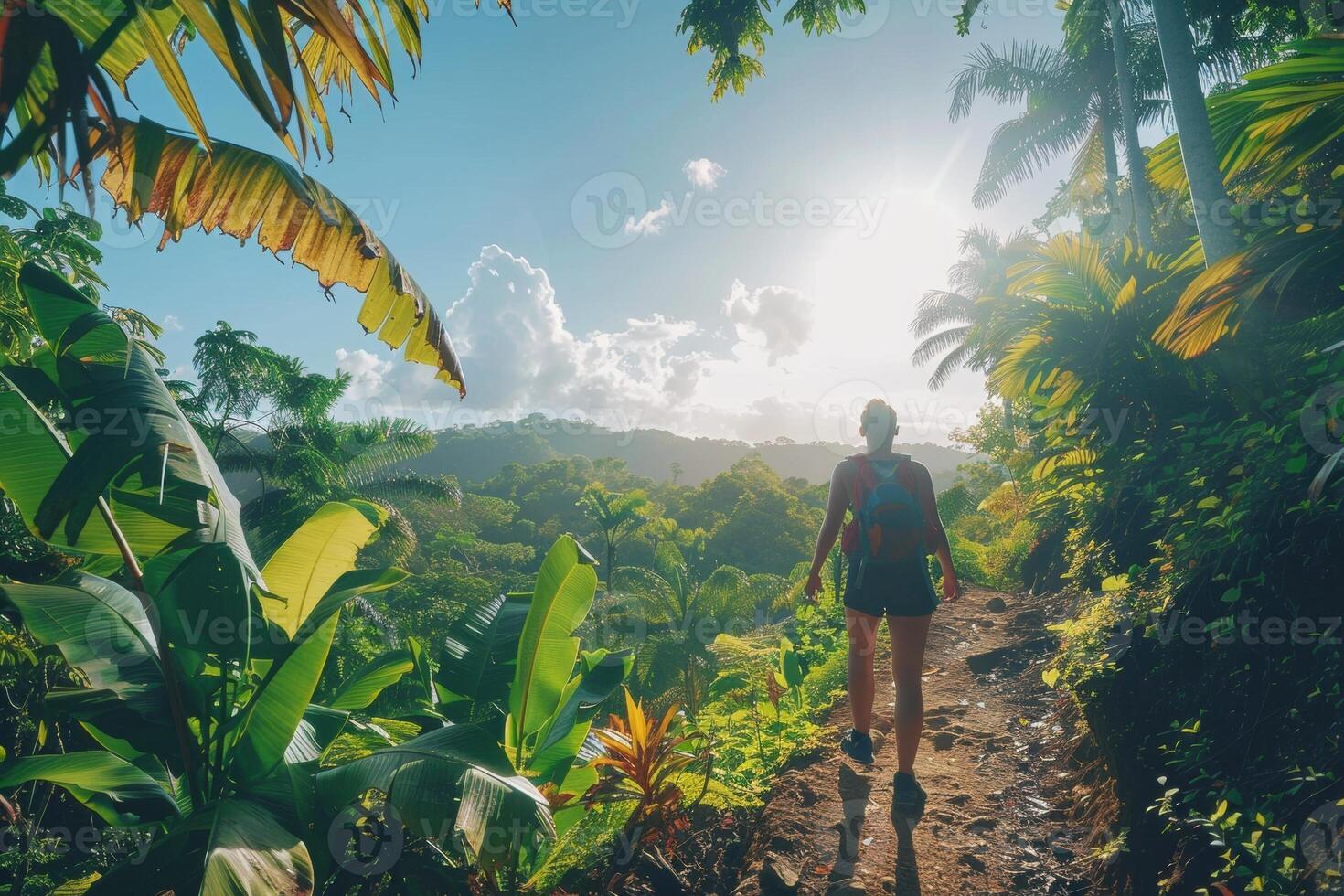 Woman hiking through lush tropical jungle with sunlight streaming through the trees. photo