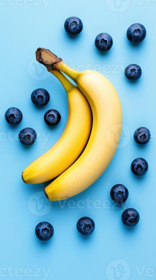 Fresh bananas and blueberries arranged on a vibrant blue background. photo