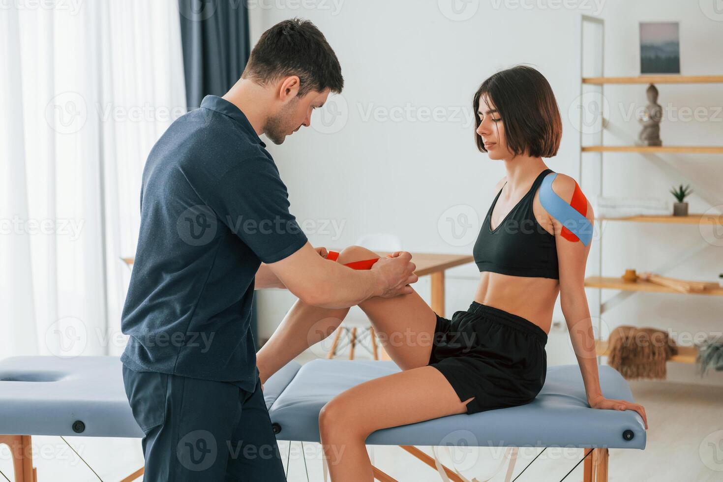 Side view., Woman visiting physiologist that putting kinesio tape on the skin photo
