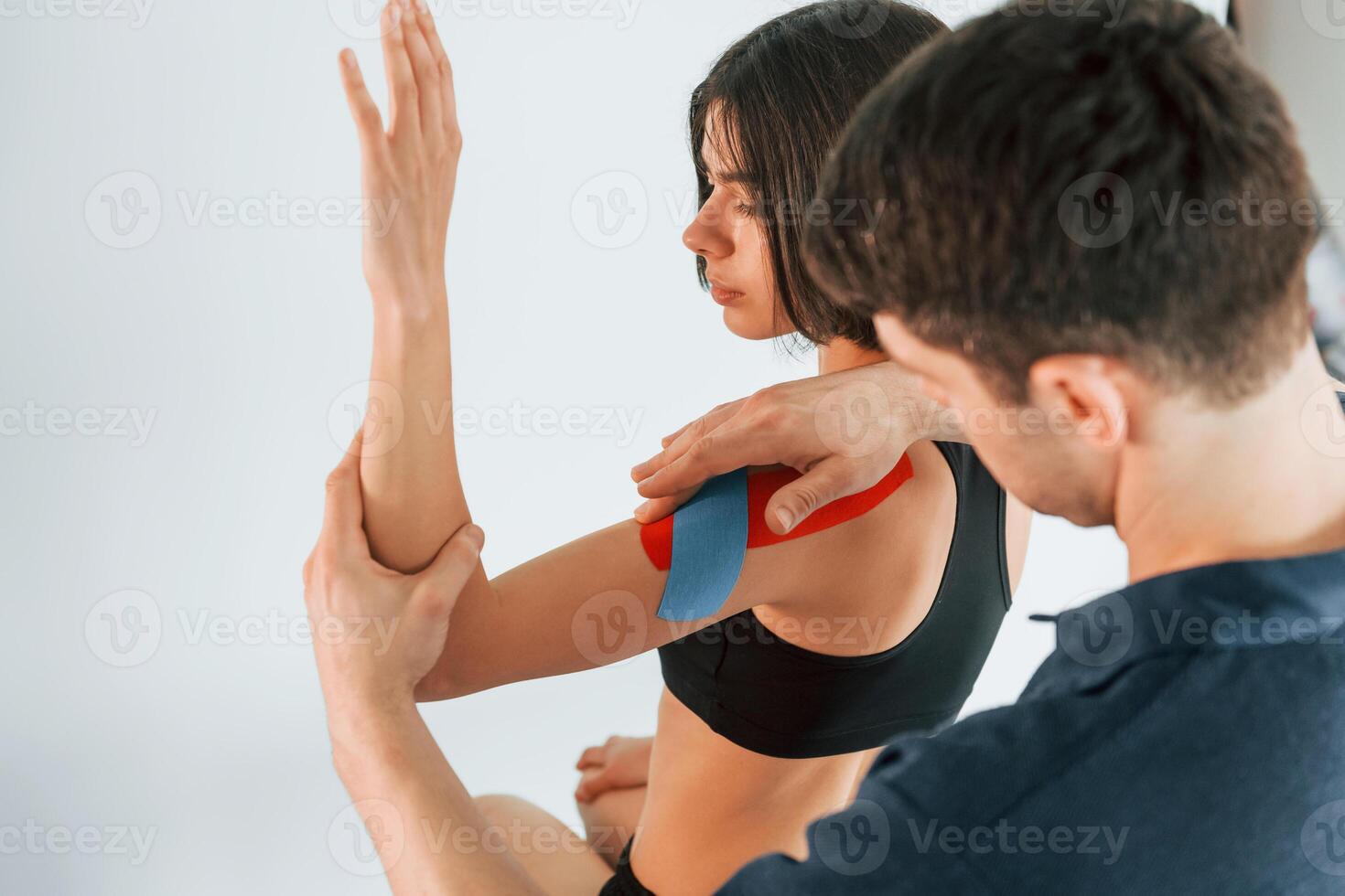 On the left hand. Woman visiting physiologist that putting kinesio tape on the skin, photo