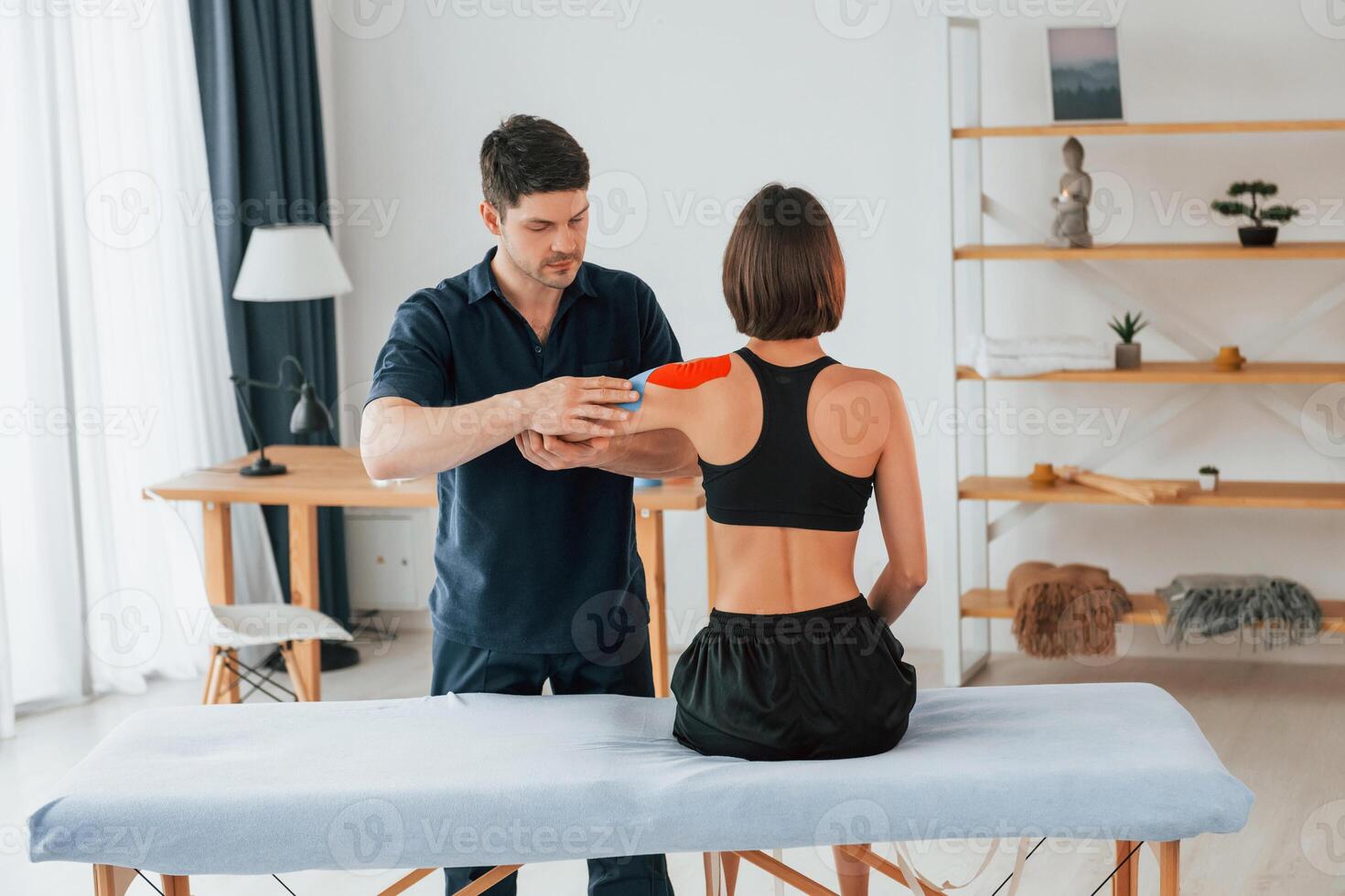 Modern background. Woman visiting physiologist that putting kinesio tape on the skin photo