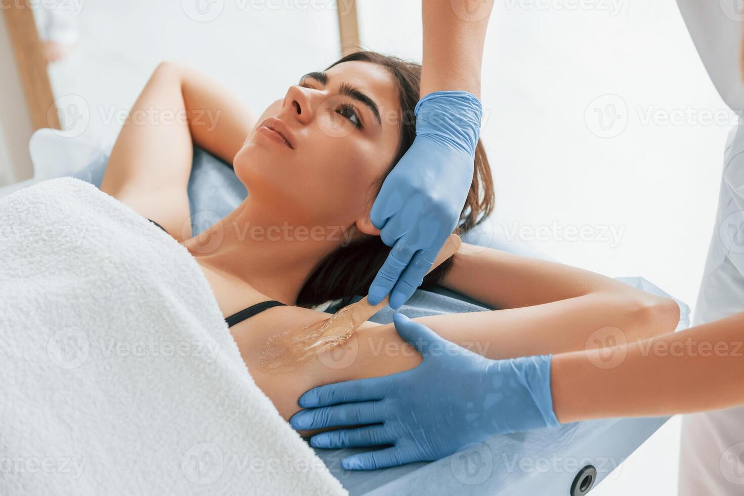 Putting cream on ,the armpits. Woman is having sugaring procedure in the clinic by female doctor photo