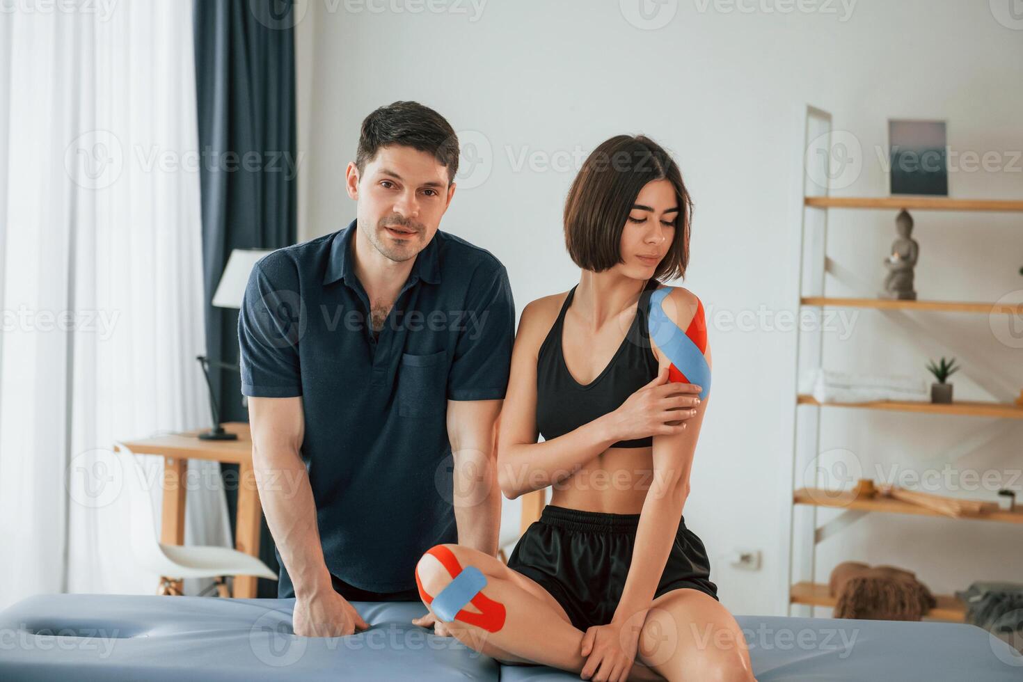 Looking at the camera,. Woman visiting physiologist that putting kinesio tape on the skin photo