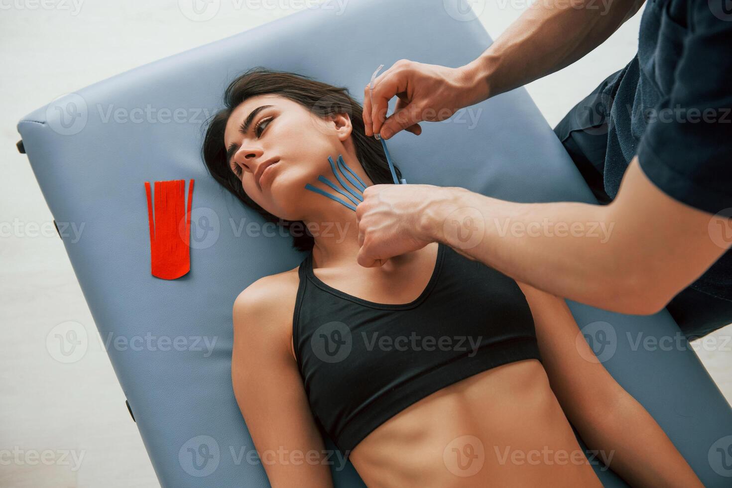 Laying down on the table,.. Woman visiting physiologist that putting kinesio tape on the skin photo